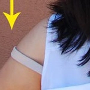 May include: A white sleeveless shirt with beige straps on the shoulders.