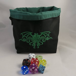 Reversible drawstring dice bag with toggle closure and square base. Ideal for D&D, board games, wargames. Features embroidered design and plain color side. Great gift for tabletop gamers