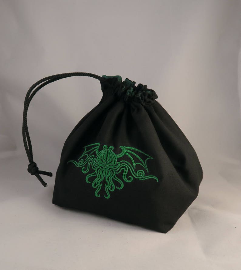 Reversible drawstring dice bag with toggle closure and square base. Ideal for D&D, board games, wargames. Features embroidered design and plain color side. Great gift for tabletop gamers