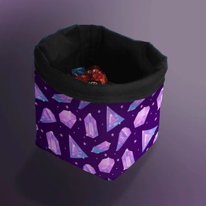 May include: A purple dice bag with a black interior and rim. The bag is covered in a pattern of stylized, glowing purple crystals and white stars. Several multi-sided dice are visible inside the bag.