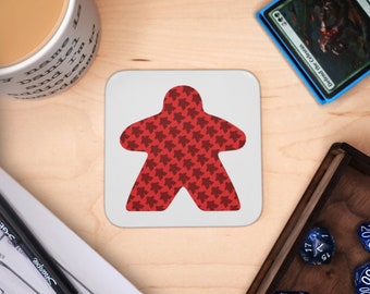 May include: A white coaster with a red meeple-shaped design. The meeple is filled with a pattern of smaller red meeples.