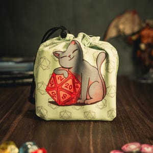 May include: A green drawstring bag with a white cat design holding a red 20-sided die. The bag has a white background with a repeating pattern of dice.