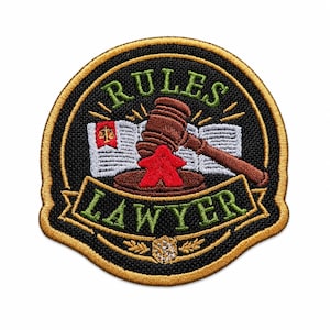 May include: A circular embroidered patch with a black background and gold border. It features a brown wooden gavel resting on a red game piece, in front of an open book with a red flag icon. The text RULES is in green above and LAWYER is in green below.