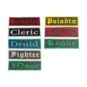 May include: Embroidered patches with fantasy RPG class names: Barbarian, Cleric, Druid, Fighter, Mage, Paladin, Ranger, and Rogue. Each patch has a black background with the class name in a contrasting colour.