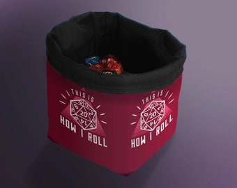 Puede incluir: Bolsa de dados roja con forro negro y un gráfico blanco de un dado de 20 caras con el texto "This is how I roll".