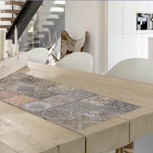 Könnte beinhalten: Ein Esstisch aus Holz mit einem gemusterten Fliesenläufer in der Mitte. Der Tisch ist aus Naturholz gefertigt und hat einen rustikalen Look. Auf dem Tisch stehen weiße Kerzen und ein Holztablett.