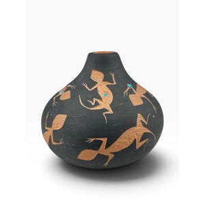 May include: A matte black rounded vase featuring etched tan lizard figures across the surface. The lizard designs are accented with small, circular, bright turquoise stone inlays. The vase has a narrow, circular opening at the top and a wide base.