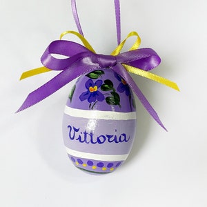 Versierd en gepersonaliseerd ei met tekst. Handgeschreven naam met bloemen. Pasen, lente en bloemencadeau. Viooltjes voor haar geschilderd