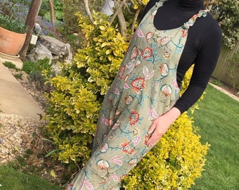 May include: A green floral print jumpsuit with a black turtleneck top. The jumpsuit has a loose fit and features a tie at the neck.