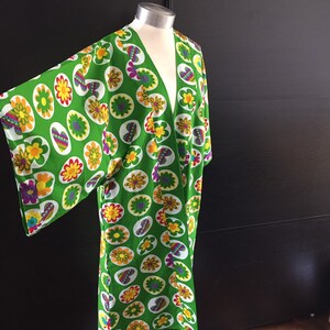 K&ouml;nnte beinhalten: Ein gr&uuml;nes Kimono mit einem bunten Blumenmuster. Das Muster zeigt Blumen, Herzen und Kreise.