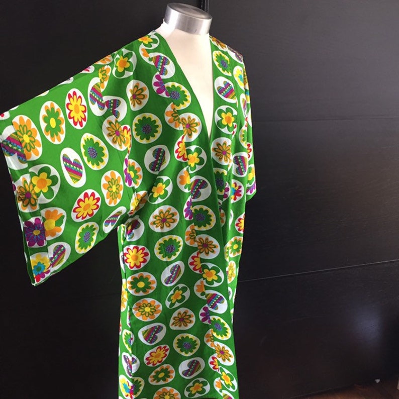 K&ouml;nnte beinhalten: Ein gr&uuml;nes Kimono mit einem bunten Blumenmuster. Das Muster zeigt Blumen, Herzen und Kreise.