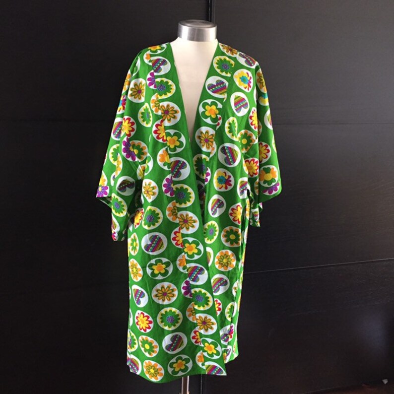K&ouml;nnte beinhalten: Ein gr&uuml;nes Kimono mit einem Blumenmuster aus bunten Blumen und Herzen. Das Kimono hat einen V-Ausschnitt und lange &Auml;rmel.