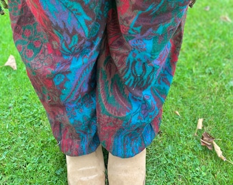 Peut inclure: Un pantalon bleu, rouge et vert à motifs avec un motif paisley. Le pantalon est plié en bas et le tissu est doux et texturé.
