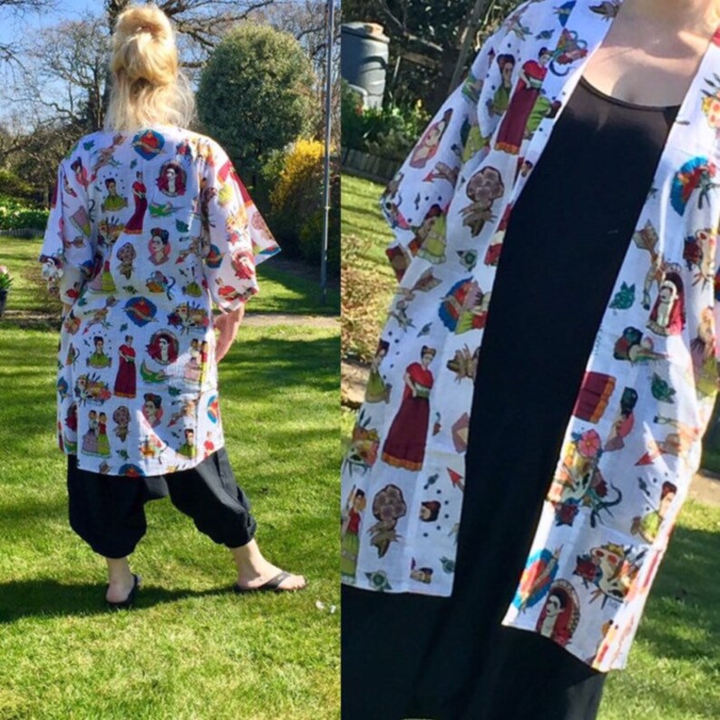 K&ouml;nnte beinhalten: Wei&szlig;er Kimono mit einem bunten Druck von Frauen und Blumen. Der Kimono hat eine lange, flie&szlig;ende Silhouette und ist perfekt zum &Uuml;berziehen &uuml;ber andere Kleidung.