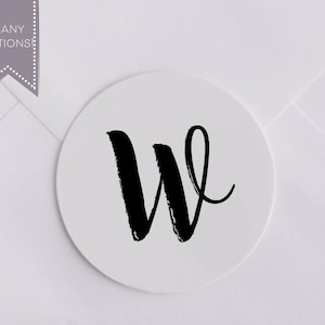 May include: A white round sticker with a black handwritten letter W.