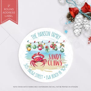 May include: A white round address label with a Christmas theme. The label features a red crab with a Santa hat on a beach with Christmas lights and ornaments. The text "The Hanson Family Sandy Claws 305 Haliwi Street Ewa Beach HI 96706" is printed on the label.
