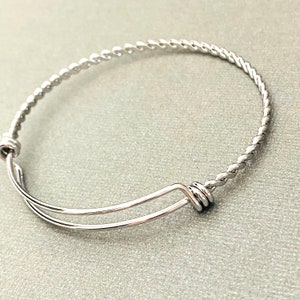 May include: A silver expandable bangle bracelet with a twisted wire design.