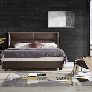Puede incluir: Una cama con estructura de cuero marr&oacute;n con cabecero y piecero. La cama est&aacute; hecha con un edred&oacute;n morado y almohadas blancas. Una l&aacute;mpara de pie negra est&aacute; en la esquina de la habitaci&oacute;n. Un cuadro abstracto en blanco y negro cuelga de la pared detr&aacute;s de la cama. Una silla marr&oacute;n con una manta beige est&aacute; en primer plano. La habitaci&oacute;n tiene un suelo de madera oscura y una alfombra con un patr&oacute;n geom&eacute;trico.