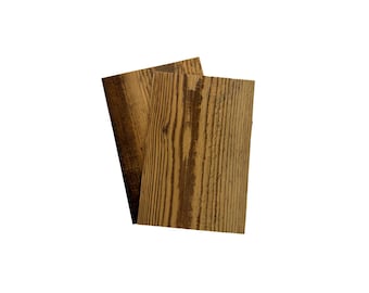 May include: Two rectangular wooden boards featuring a prominent brown wood grain pattern. The boards are layered slightly offset from one another, displaying a natural texture with darker brown streaks running vertically across the surface.