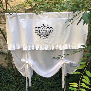 Könnte beinhalten: Weißer, durchsichtiger Vorhang mit einem Rüschen-Oberteil und Bindebändern. Der Vorhang hat ein schwarzes, gesticktes Logo mit der Aufschrift "Chateau Ville de Paris 1802".