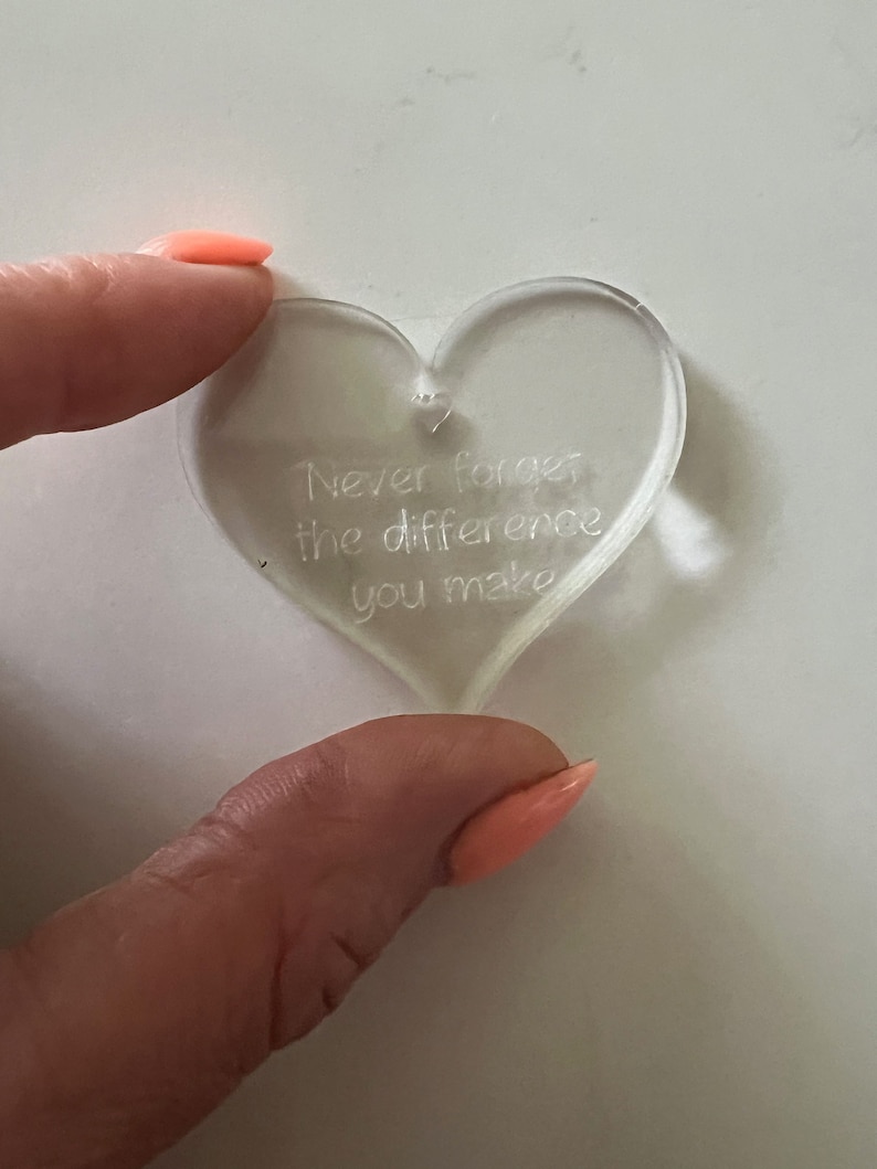 2 fingers holding a clear heart that reads "never forget the difference you make" with a small heart shaped hole at the top