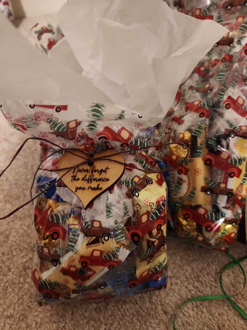 a goodie bag with a wood heart attached to it that reads "never forget the difference you make" in cursive font