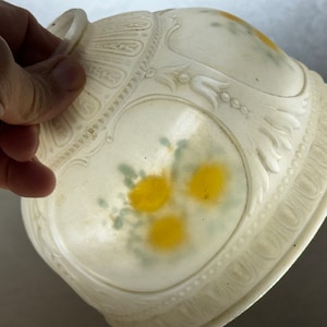 May include: White glass lampshade with a floral design. The shade has a raised, ornate pattern around the edge and a delicate floral design in yellow and green.