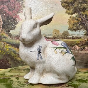 May include: White ceramic rabbit figurine with a crackled glaze and floral and dragonfly designs.