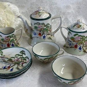 May include: A vintage Japanese tea set with a green and white floral design. The set includes a teapot, creamer, sugar bowl, and two teacups and saucers.