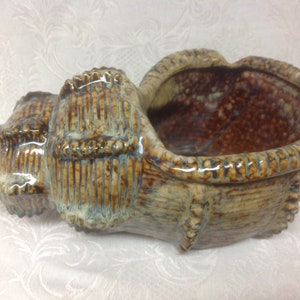 May include: A ceramic seashell planter with a brown and white glaze. The planter has a textured surface and a wide opening.