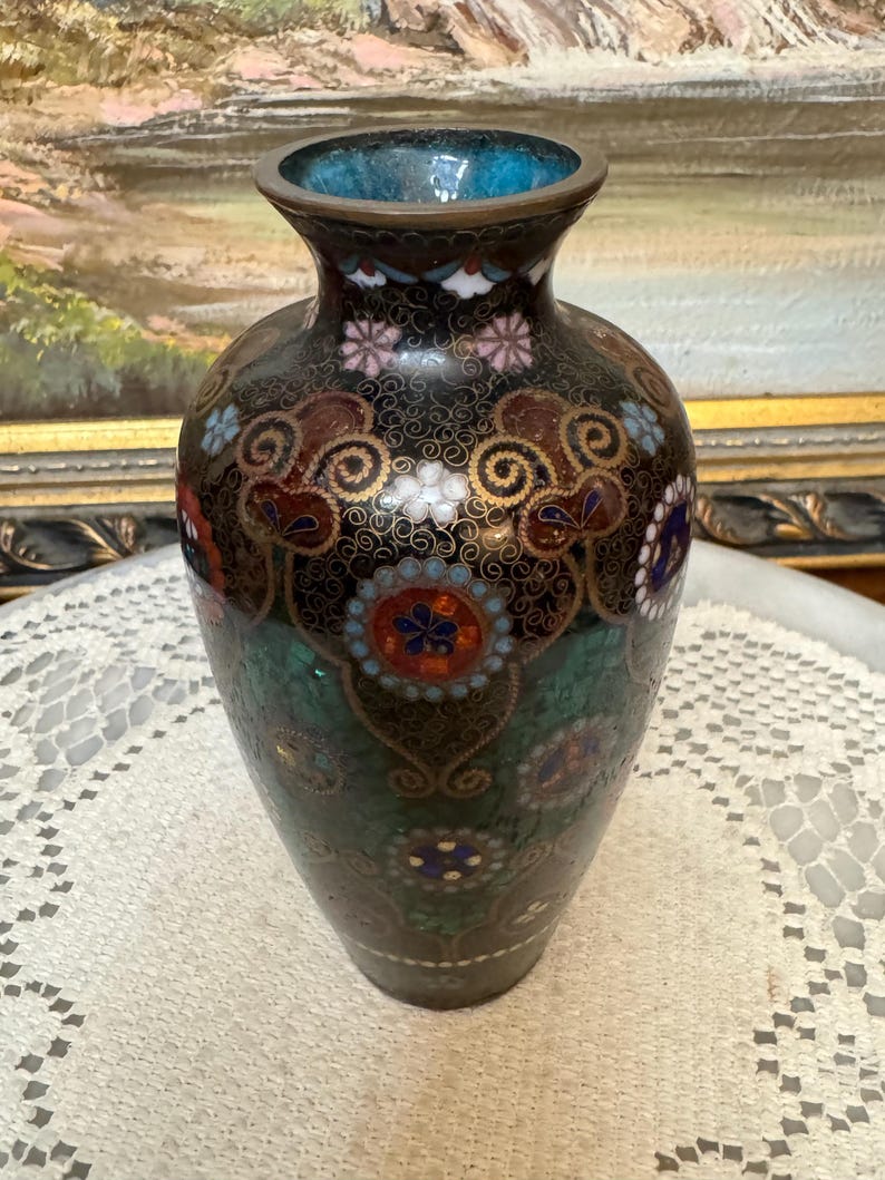 May include: A black and green cloisonn&eacute; vase with a floral design. The vase is decorated with gold, red, white, and blue enamel.