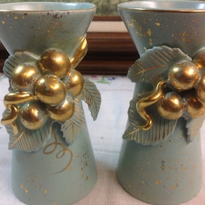 May include: A pair of light blue ceramic vases with gold accents. The vases are decorated with a grapevine design and have a speckled glaze.