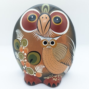 Op de afbeelding: Handbeschilderd keramiek uilenbeeldje in bruin, oranje, rood en groen. De uil heeft grote ogen en een gedetailleerd ontwerp.