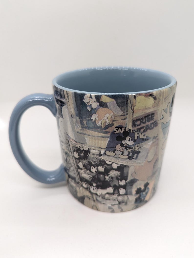 Op de afbeelding: Een keramische mok met een lichtblauw handvat en interieur. De buitenkant toont een collage van vintage Mickey Mouse-afbeeldingen en de tekst "SAFE BRIGADE FL". Een klassiek Disney-thema verzamelobject.