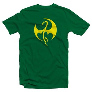 Op de afbeelding: Een groen T-shirt met een geel drakenlogo. Het logo is een gestileerde draak met vleugels en een staart.