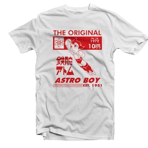 May include: Red and white graphic t-shirt featuring Astro Boy, a Japanese manga character, flying with a rocket booster. The text "THE ORIGINAL" is at the top, and "ASTRO BOY EST. 1951" is at the bottom. The text "鉄腕アトム" is in Japanese.