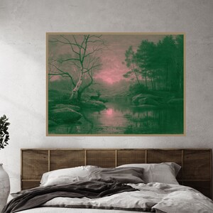 May include: A framed landscape print featuring a serene forest scene with a river, trees, and deer. The artwork has a green and pink color palette, creating a tranquil and natural aesthetic. The print is displayed above a bed.