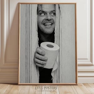 May include: Monochrome framed print depicting a man peering through a door, clutching a toilet roll. The image is a humorous take on a well-known film scene. The print is labelled "LUXX POSTERS curated vintage art."