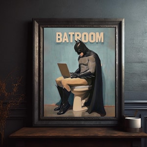 May include: A framed illustration of a superhero in a black cape and mask sitting on a toilet with a laptop on their lap. The text "BATROOM" is printed above the superhero.
