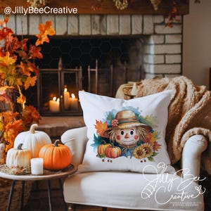 May include: A white throw pillow with a watercolor illustration of a scarecrow with a straw hat, sunflowers, and fall leaves. The pillow is sitting on a white couch in front of a fireplace.