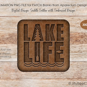 May include: A brown, square patch design with the words "LAKE LIFE" cut out, featuring a tree, fish, and waves. The design is on a textured background, with the text "Digital Design: Saddle Leather with Embossed Design". The image is on a wooden surface.
