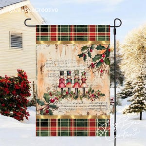 Puede incluir: Una bandera de jardín con temática navideña con un borde de cuadros rojos y verdes. El centro presenta una ilustración de estilo vintage de cuatro soldados cascanueces de pie en una rama con bayas de acebo. El fondo es una hoja de música descolorida.