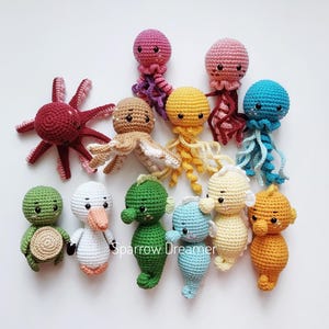 May include: A collection of crocheted sea creature toys, including an octopus, jellyfish, seahorse, turtle, and a swan. The toys are all brightly colored and have cute faces.