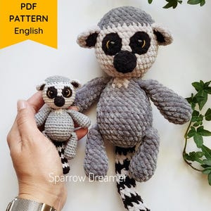 May include: Two grey and white crochet lemur toys. One is held in a hand, the other is larger and stands upright. The lemurs have black and white striped tails and black eyes. The image includes text that says "PDF PATTERN English" and "Sparrow Dreamer".