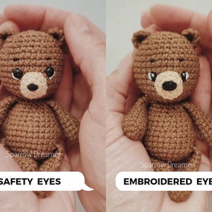 Op de afbeelding: Twee gehaakte teddyberen in bruin garen, vastgehouden in handen. E&eacute;n beer heeft veiligheidsoogjes, de andere heeft geborduurde ogen. Beide hebben een tan snuit en een zwarte neus. De teksten "SAFETY EYES" en "EMBROIDERED EYES" staan in tekstballonnen.
