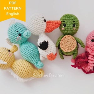 Op de afbeelding: Een verzameling handgemaakte gehaakte zeedieren, waaronder een zeepaardje, een eend, een schildpad en een kwal. De speelgoedjes zijn in verschillende kleuren, zoals blauw, geel, groen, wit en roze. De afbeelding bevat de tekst "PDF PATTERN English" en de naam "Sparrow Dreamer".