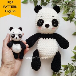 Op de afbeelding: Twee gehaakte pandaberen, een grote en een kleine. De grotere panda is wit met zwarte oren, ogen, neus en poten. De kleinere panda is hetzelfde ontwerp, maar kleiner. Beide panda's zitten op een wit oppervlak.