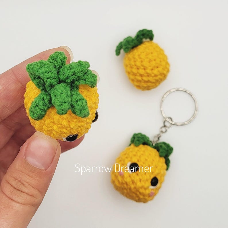 Pode incluir: Chaveiros e berloques de abacaxi de croch&ecirc; em amarelo e verde. Um chaveiro &eacute; preso a um anel de prata. Os chaveiros e berloques t&ecirc;m olhos pretos e bochechas rosadas. O texto "Sparrow Dreamer" &eacute; vis&iacute;vel.