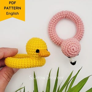 Peut inclure: Deux jouets crochetés : un canard jaune et un flamant rose. Le canard a un bec orange. Le flamant rose a un cou en forme d'anneau et un bec blanc et noir. L'image comprend le texte "PDF PATTERN English".