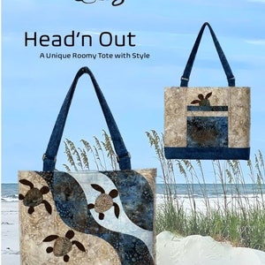 May include: A blue and brown tote bag with a sea turtle design. The bag has a large pocket on the front and a zipper closure. The bag is on a beach with sand and seagrass.